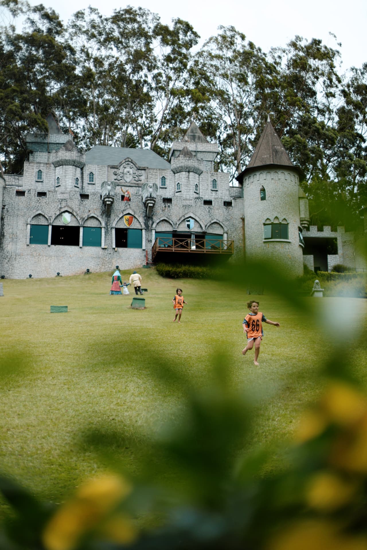Crianças correndo no gramado em frente ao castelo medieval